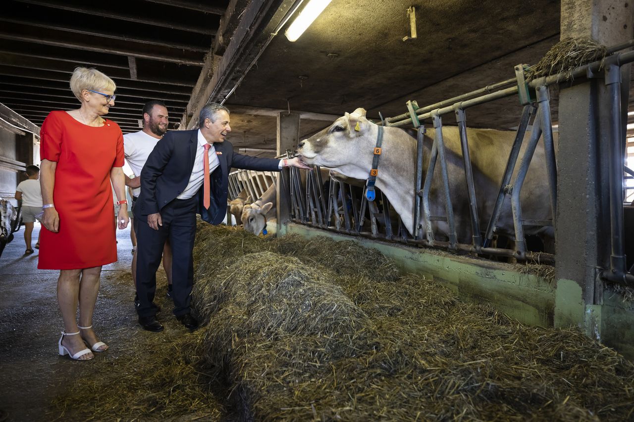 Le président de la Confédération Ignazio Cassis, son épouse Paola Rodoni et l'exploitant Serge Duperrex lors d'un brunch à la ferme Stoeckweid, à Knonau (ZH), à l'occasion du 1er Août. [Michael Buholzer - KEYSTONE]